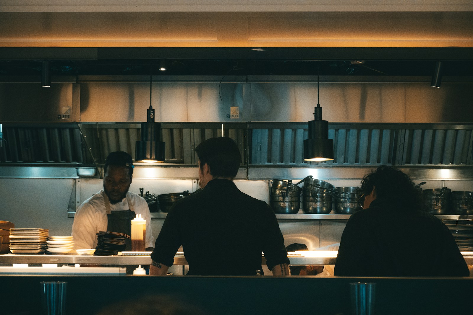 Chefs prepare food in a dimly lit restaurant.