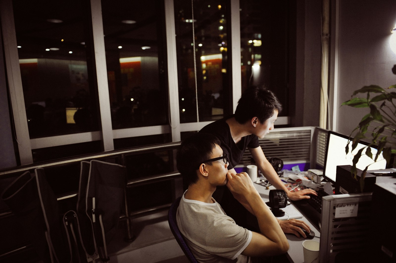 Two men working on computers at night
